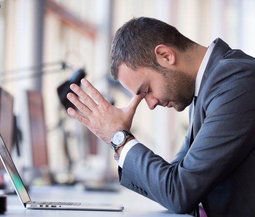 frustrated young business man working on laptop computer at office